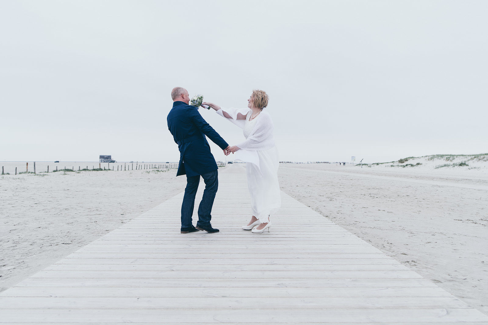 Hochzeitsfotograf Brautpaar lachend am Strand Pfahlbauten in Sankt Peter-Ording