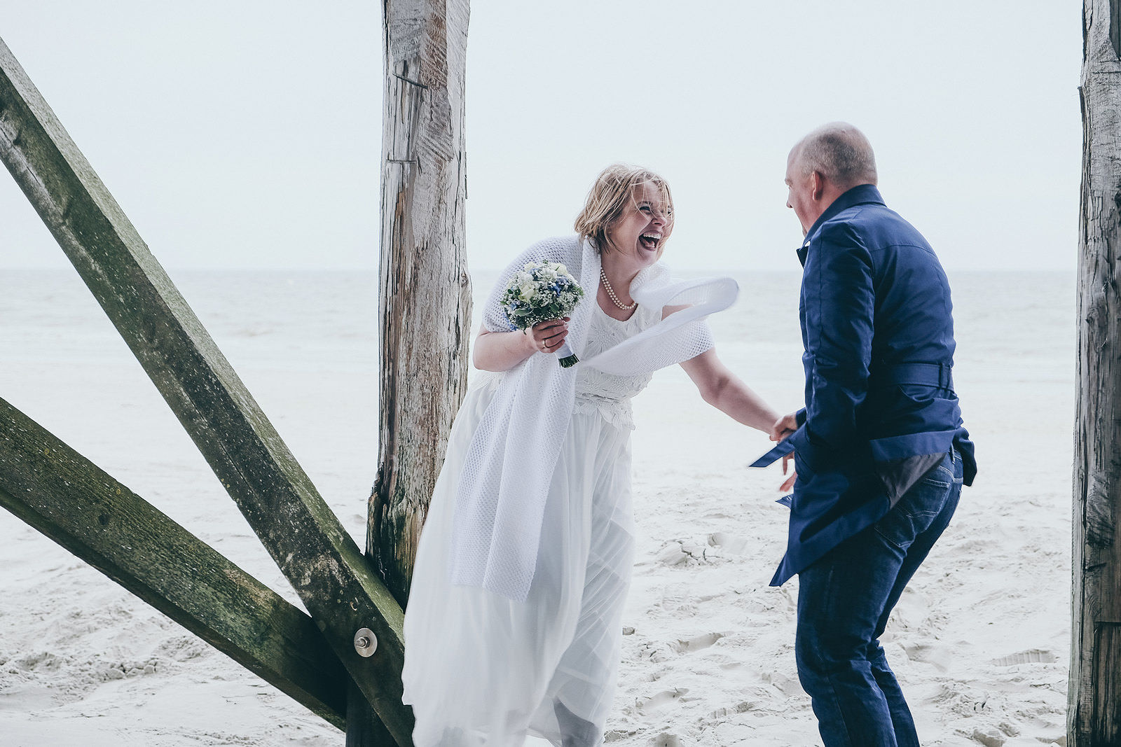 lHochzeitsfotograf achendes Brautpaar am Strand Pfahlbauten in Sankt Peter-Ording